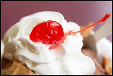 Ice cream sunday with large red cherry on top.