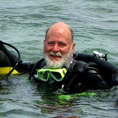 Reid Joyce in scuba gear floating in water and smiling at camera.