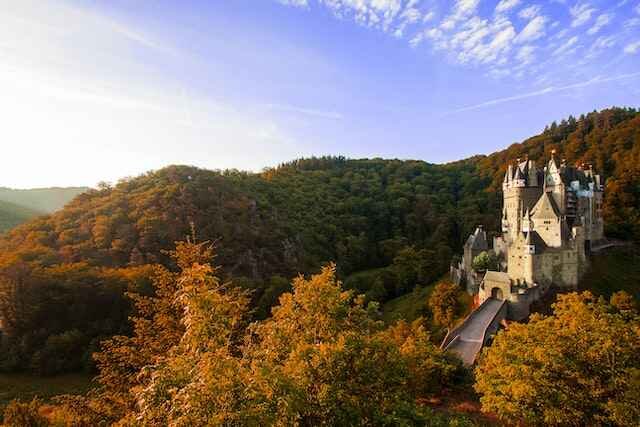 Photo of German castle surrounded by trees in the mountains.